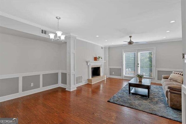 living room featuring ceiling fan with notable chandelier, wood-type flooring, and crown molding