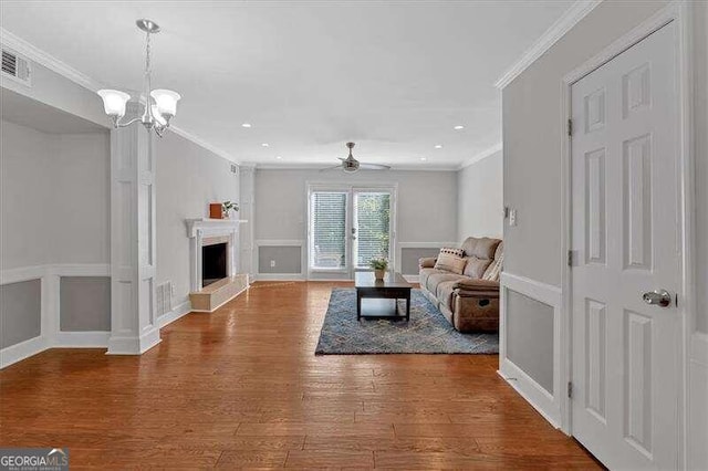 living room featuring ceiling fan with notable chandelier, hardwood / wood-style flooring, and crown molding