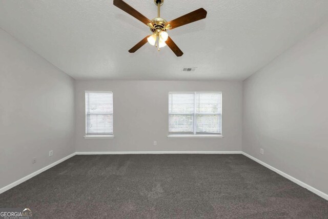 carpeted empty room with a wealth of natural light, ceiling fan, and a textured ceiling