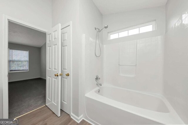 bathroom featuring a wealth of natural light, tub / shower combination, and hardwood / wood-style flooring