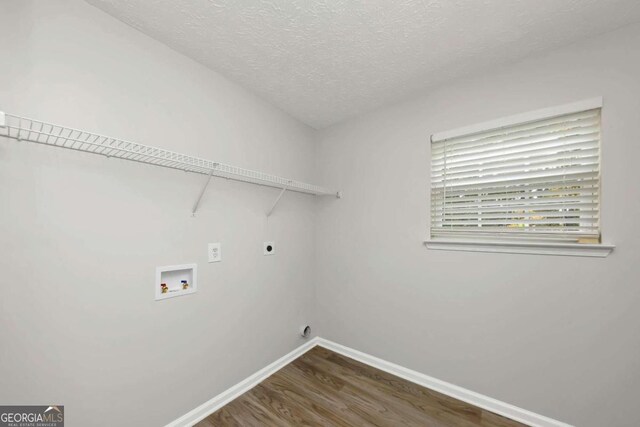 laundry room featuring electric dryer hookup, dark hardwood / wood-style flooring, washer hookup, and a textured ceiling