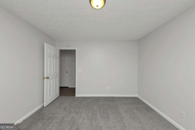 unfurnished room with carpet and a textured ceiling