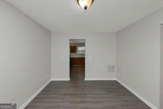 empty room featuring dark wood-type flooring and a textured ceiling