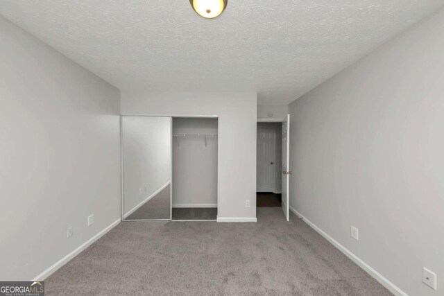 unfurnished bedroom with carpet flooring, a textured ceiling, and a closet