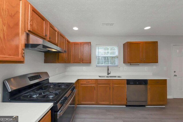 kitchen featuring wood-type flooring, a textured ceiling, stainless steel appliances, and sink