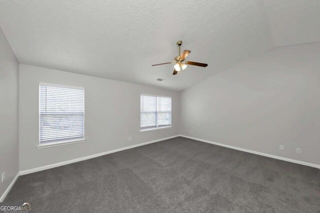 carpeted spare room featuring vaulted ceiling, ceiling fan, and a textured ceiling