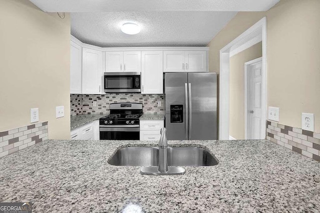 kitchen with white cabinets, sink, tasteful backsplash, stainless steel appliances, and light stone counters