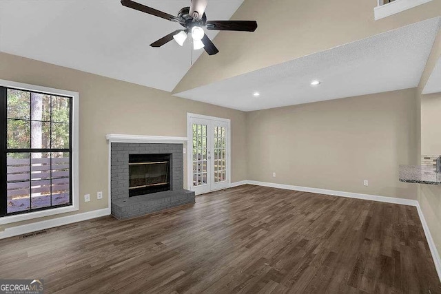 unfurnished living room with ceiling fan, a brick fireplace, dark hardwood / wood-style flooring, high vaulted ceiling, and a textured ceiling