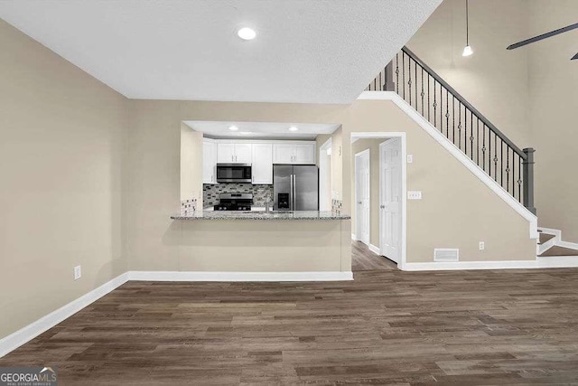 kitchen with light stone counters, white cabinets, stainless steel appliances, and dark hardwood / wood-style floors