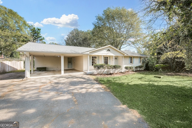 ranch-style home featuring aphalt driveway, brick siding, a front yard, fence, and a carport