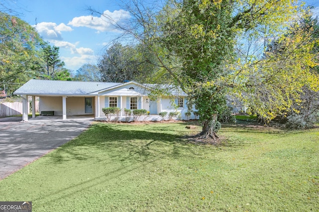 view of front of house featuring a carport, aphalt driveway, a front yard, and fence