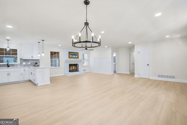 interior space with recessed lighting, visible vents, light wood-style flooring, a brick fireplace, and a sink