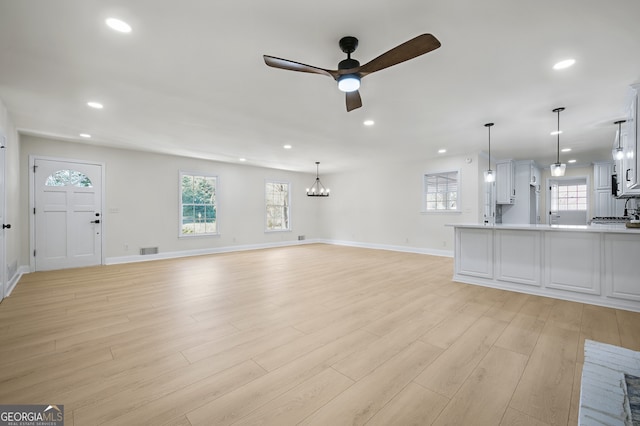 unfurnished living room featuring light wood-style floors, recessed lighting, visible vents, and ceiling fan with notable chandelier