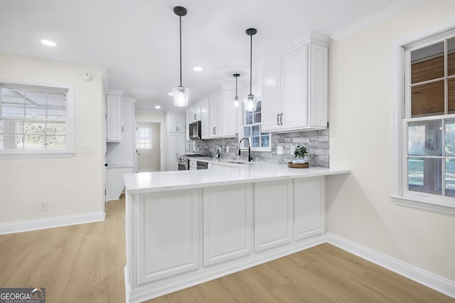 kitchen featuring white cabinets, a peninsula, stainless steel appliances, light countertops, and backsplash