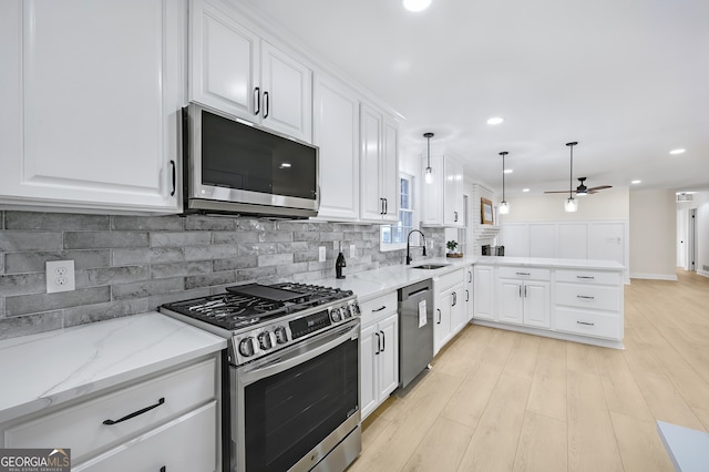 kitchen featuring stainless steel appliances, tasteful backsplash, ceiling fan, a sink, and a peninsula