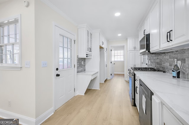 kitchen featuring light stone countertops, white cabinetry, appliances with stainless steel finishes, and baseboards