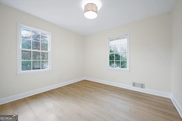 empty room with visible vents, baseboards, and wood finished floors