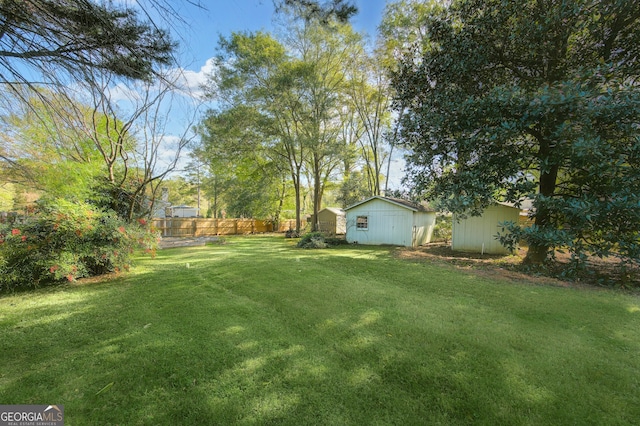 view of yard featuring an outbuilding, fence, and a storage unit