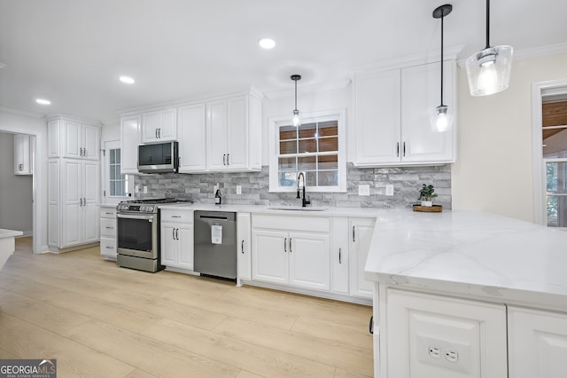 kitchen featuring stainless steel appliances, white cabinets, a sink, and backsplash