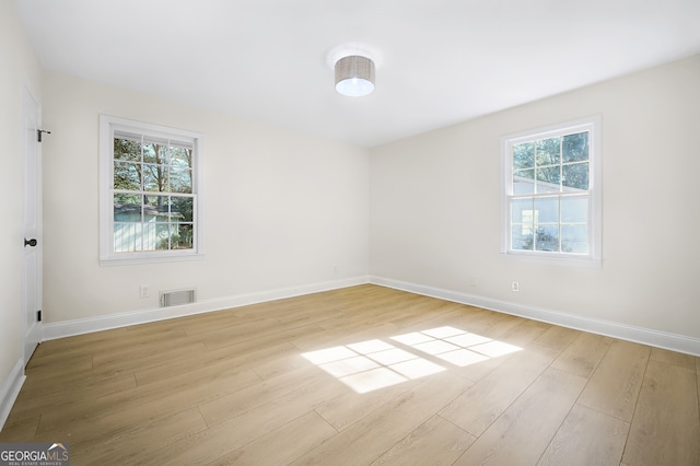 spare room with baseboards, visible vents, and wood finished floors