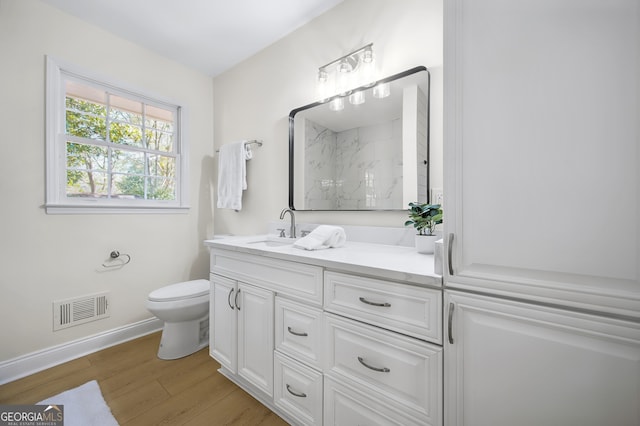 bathroom featuring visible vents, toilet, vanity, wood finished floors, and walk in shower