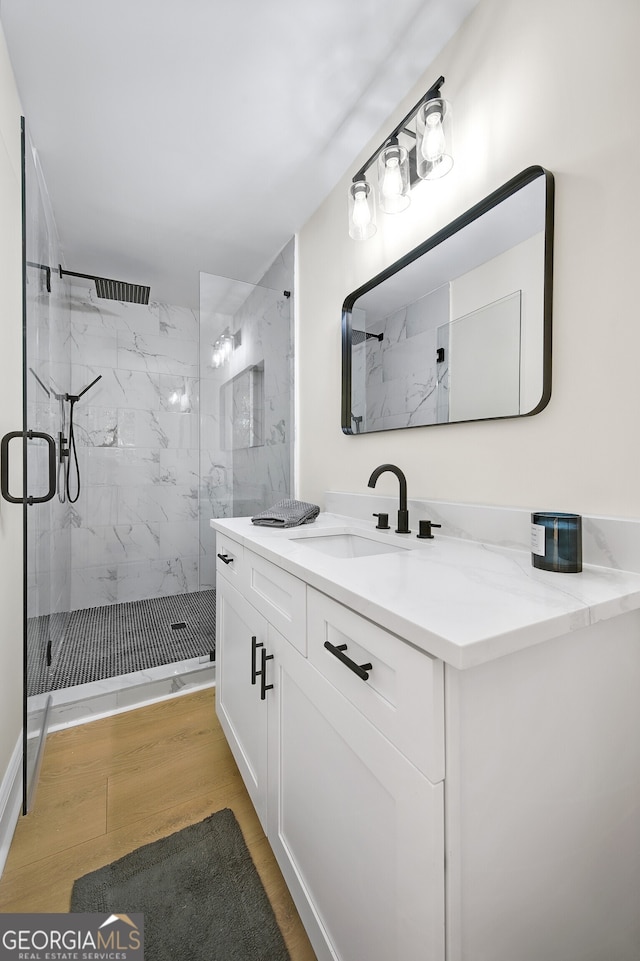 bathroom featuring vanity, a marble finish shower, and wood finished floors