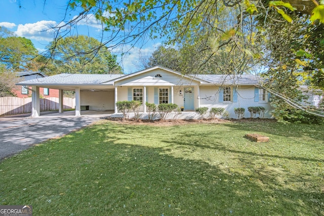 single story home with an attached carport, aphalt driveway, brick siding, fence, and a front yard