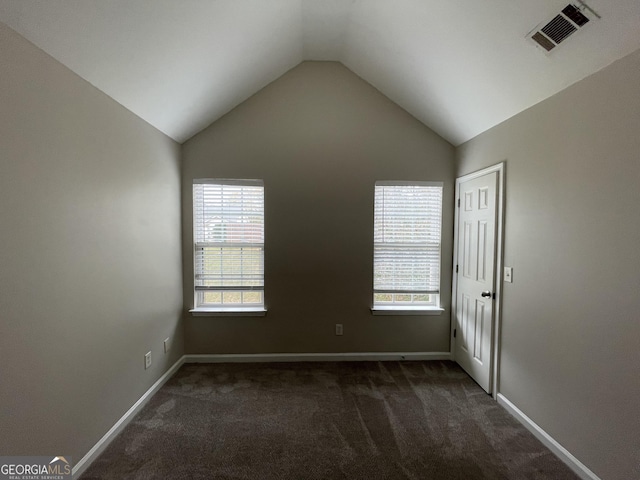 carpeted empty room featuring vaulted ceiling