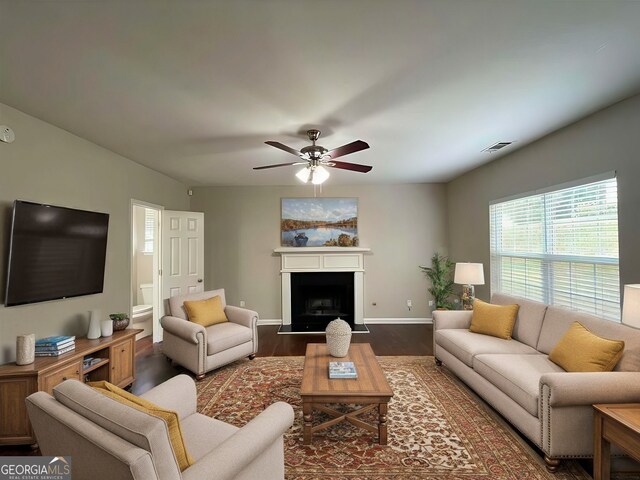 living room featuring dark wood-type flooring and ceiling fan