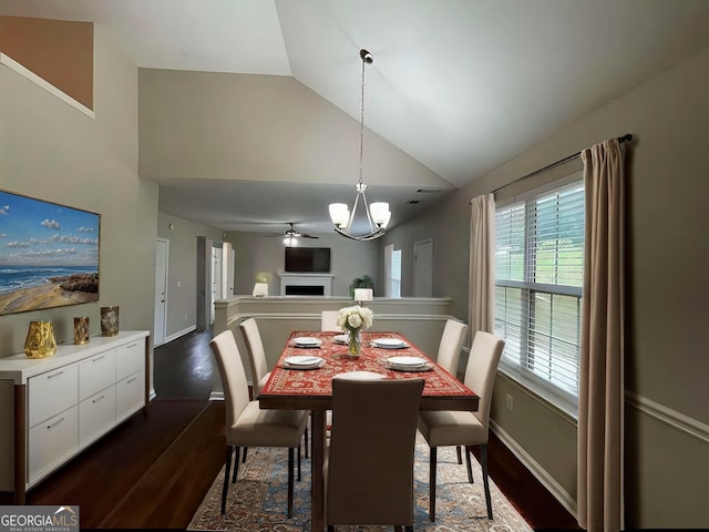 dining room with a healthy amount of sunlight, ceiling fan with notable chandelier, lofted ceiling, and dark hardwood / wood-style floors