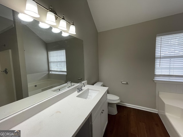 bathroom featuring toilet, a tub, vaulted ceiling, hardwood / wood-style floors, and vanity