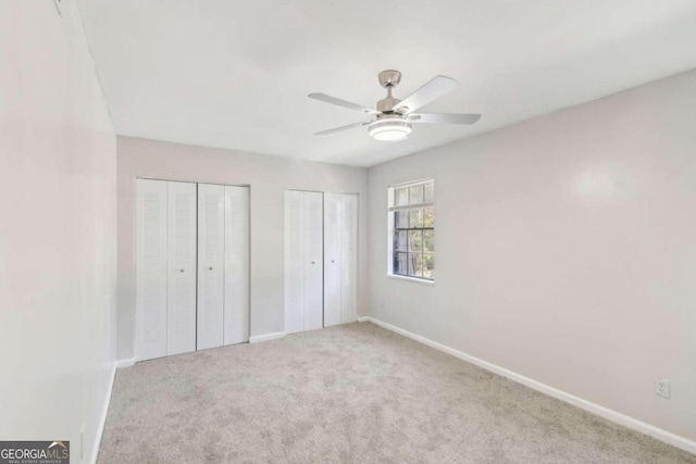 unfurnished bedroom with ceiling fan, carpet floors, and multiple closets