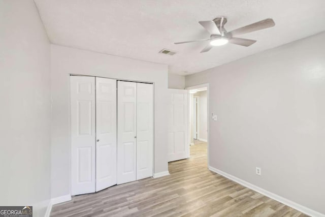 unfurnished bedroom with light hardwood / wood-style floors, a closet, and ceiling fan