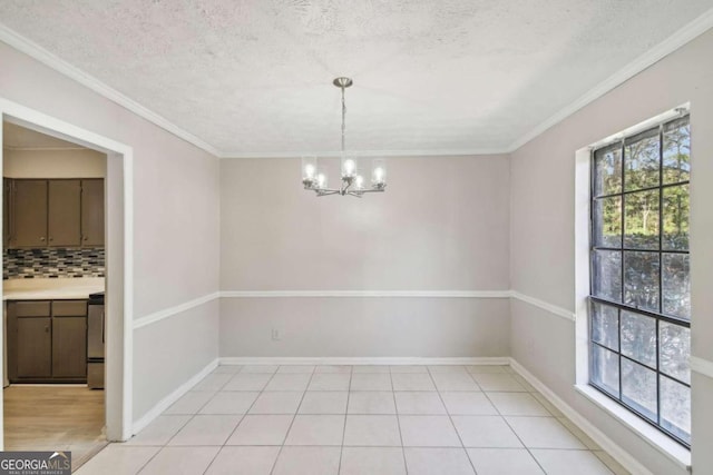 unfurnished dining area with a textured ceiling, ornamental molding, and a notable chandelier