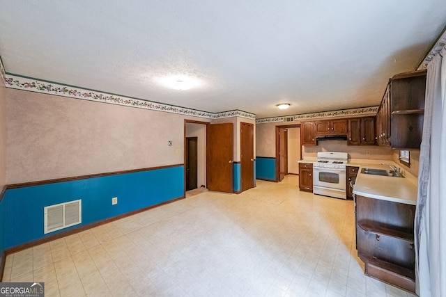 kitchen featuring white range with gas cooktop, sink, and a textured ceiling