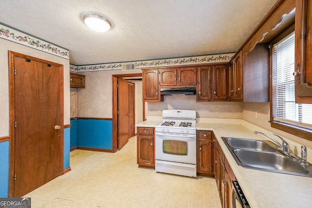 kitchen featuring dishwasher, a textured ceiling, white gas range oven, and sink