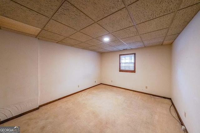 basement featuring a paneled ceiling and carpet