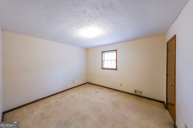 unfurnished room with light colored carpet and a textured ceiling