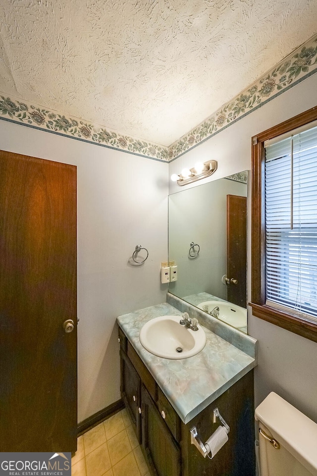 bathroom featuring vanity, toilet, tile patterned flooring, and a textured ceiling