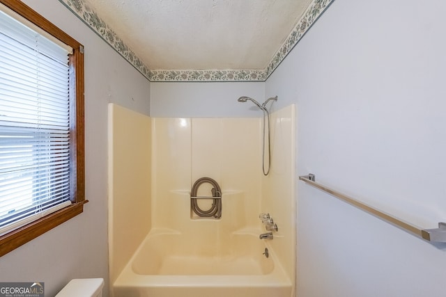 bathroom featuring  shower combination and a textured ceiling