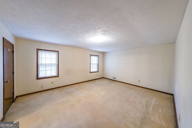 unfurnished room featuring a textured ceiling and light colored carpet