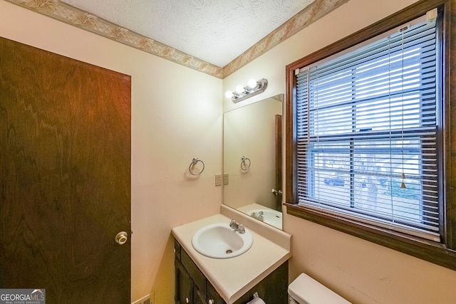 bathroom featuring vanity, toilet, and a textured ceiling