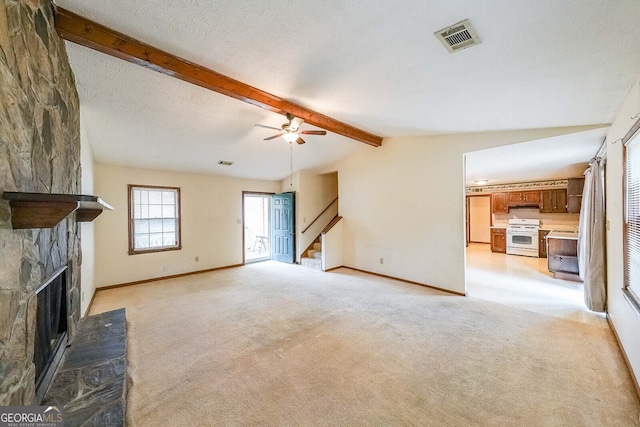 unfurnished living room featuring ceiling fan, a fireplace, light colored carpet, and lofted ceiling with beams