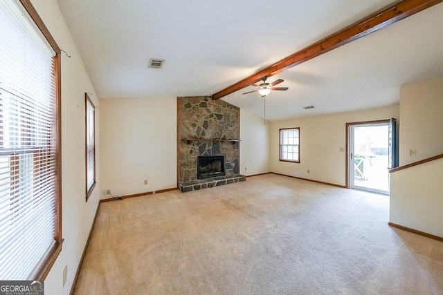 unfurnished living room featuring lofted ceiling with beams, light colored carpet, a stone fireplace, and ceiling fan