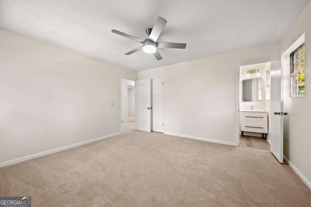 unfurnished bedroom featuring ceiling fan, ensuite bathroom, and light carpet