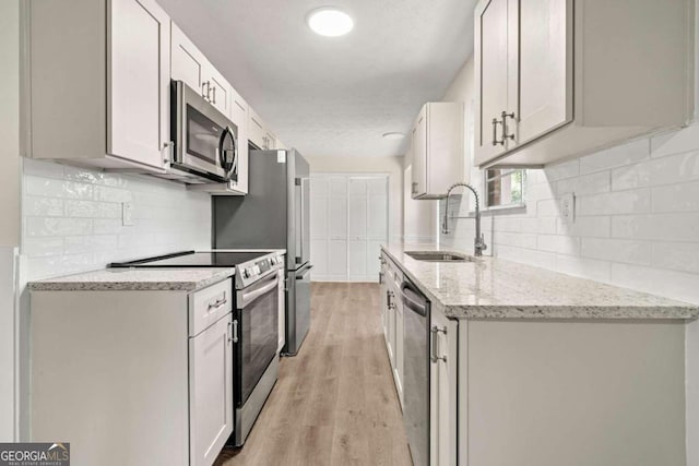 kitchen with light hardwood / wood-style flooring, stainless steel appliances, white cabinetry, and sink