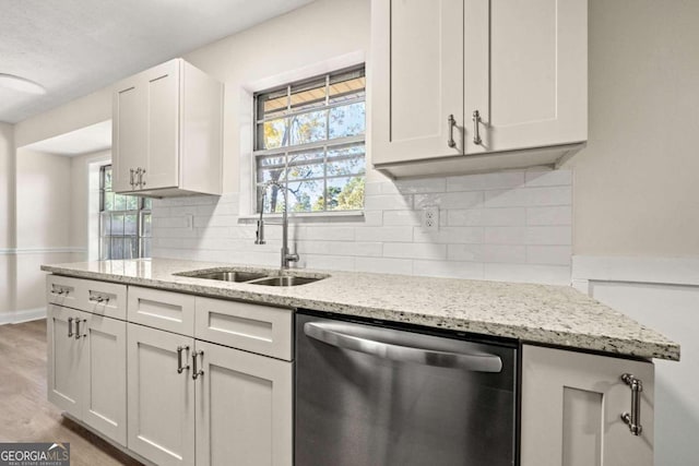 kitchen featuring sink, white cabinets, dishwasher, light stone counters, and hardwood / wood-style floors