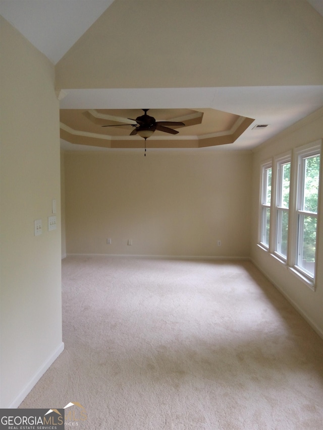 carpeted spare room featuring ceiling fan, a raised ceiling, and ornamental molding