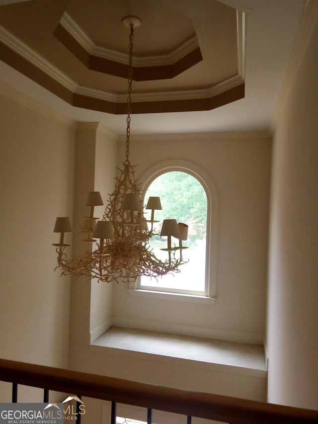 interior details featuring a tray ceiling, an inviting chandelier, and crown molding