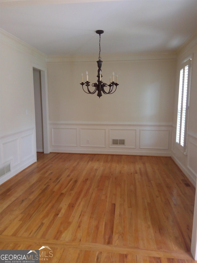 spare room featuring a chandelier, crown molding, and light hardwood / wood-style floors